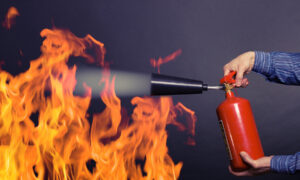 Male hand with a fire extinguisher extinguish the fire.